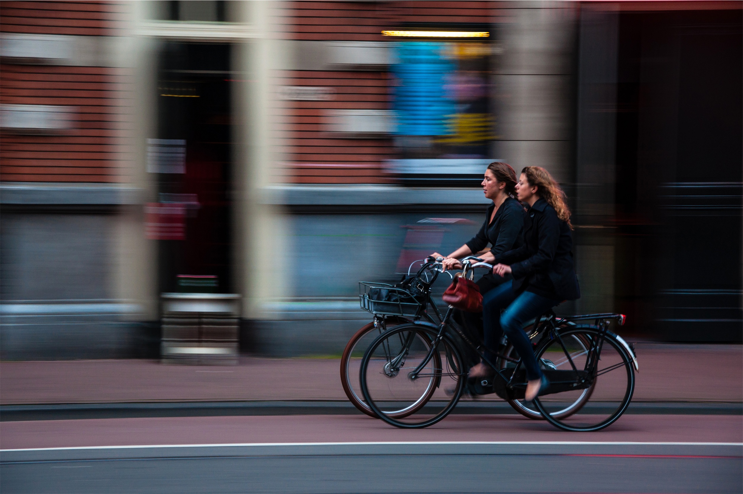 Två cyklister på cykelbana i stad.