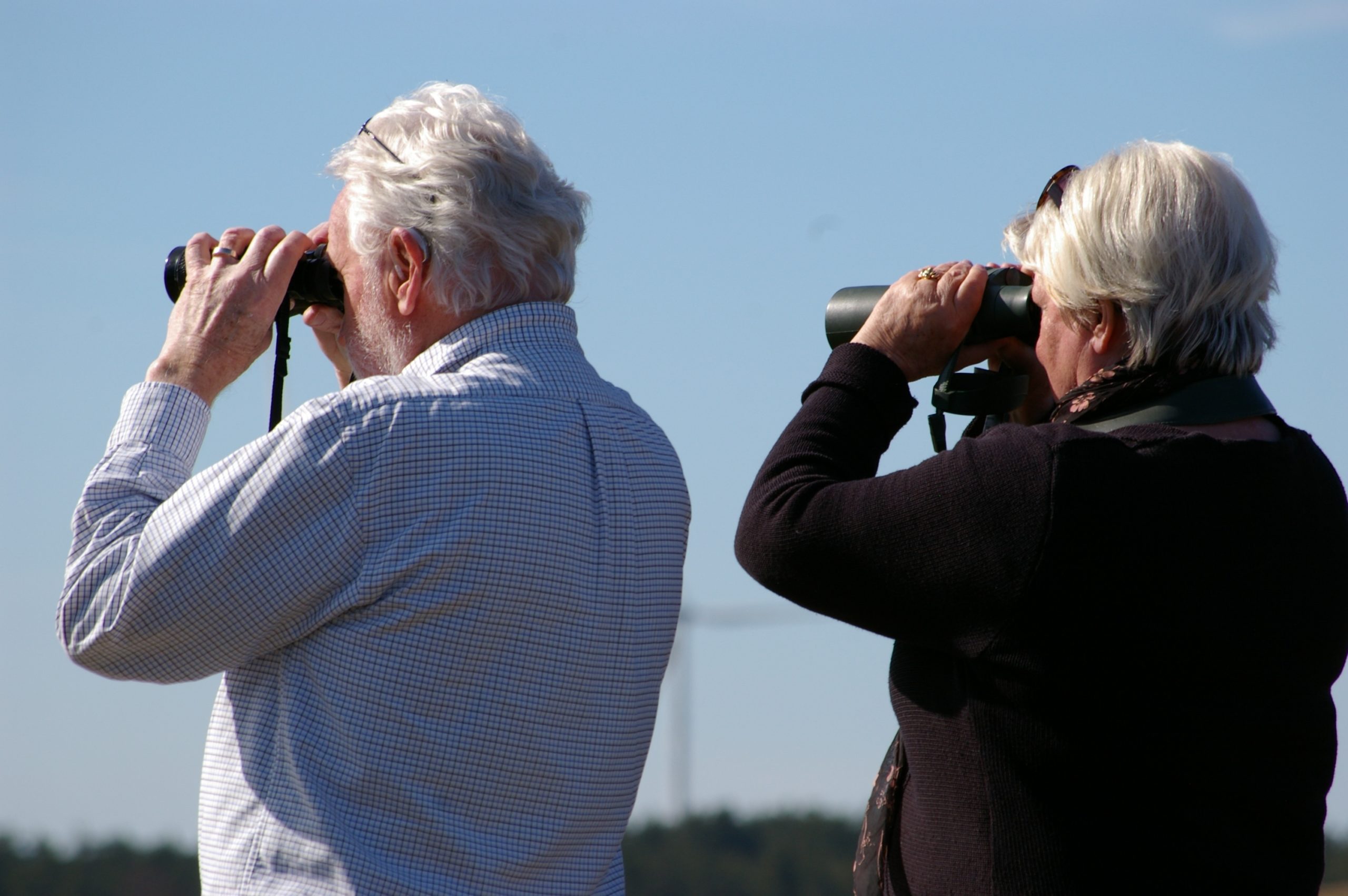 Två äldre personer som spanar i kikare.