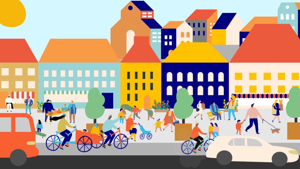 Bil- och cykelväg full med människor som cyklar, går, hälsar på varandra och barn som leker. I bakgrunden färggranna hus.